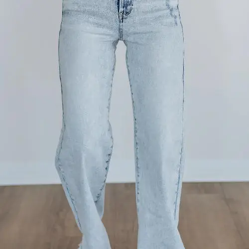 Light blue denim jeans with a straight leg cut, worn by a person standing on a wooden floor.