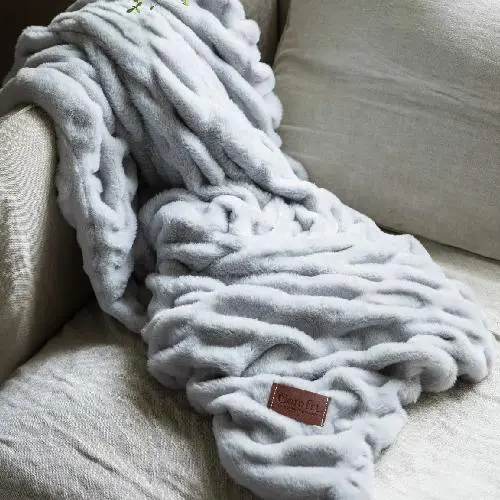 Soft, chunky knit blanket draped over a sofa.